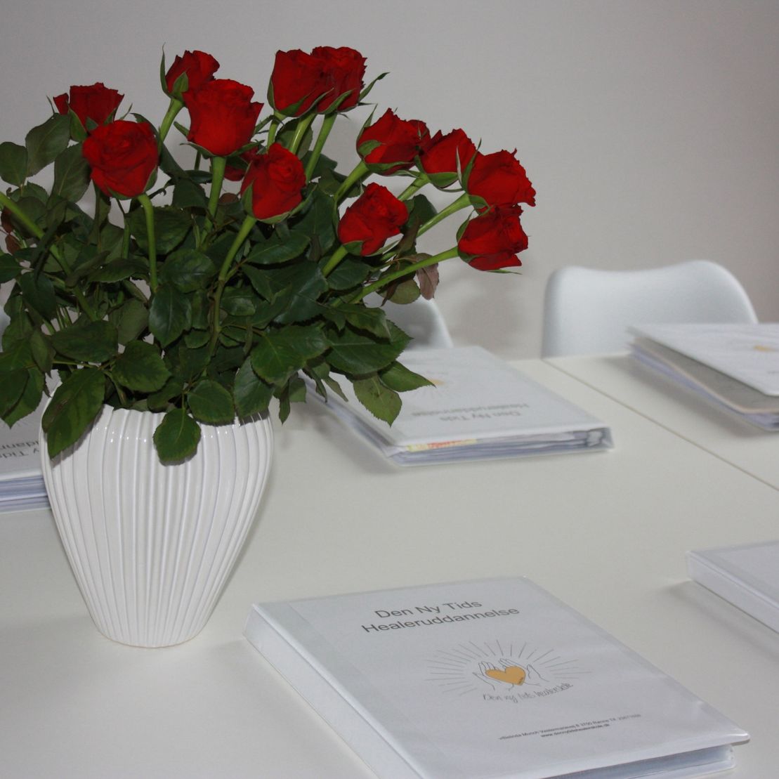 Roser i en vase og undervisningsmateriale fra Den Ny Tids Healerskole
